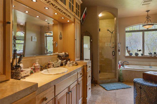 Bathroom with a stall shower, a garden tub, vanity, recessed lighting, and tile patterned floors | Image 34