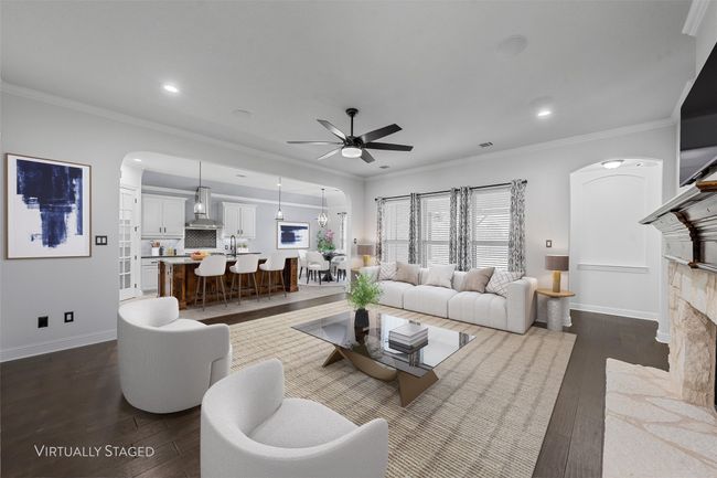 Living room with arched walkways, a ceiling fan, dark wood-type flooring, a fireplace, and recessed lighting | Image 4