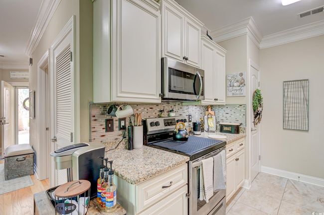 Kitchen featuring visible vents, crown molding, baseboards, decorative backsplash, and appliances with stainless steel finishes | Image 7