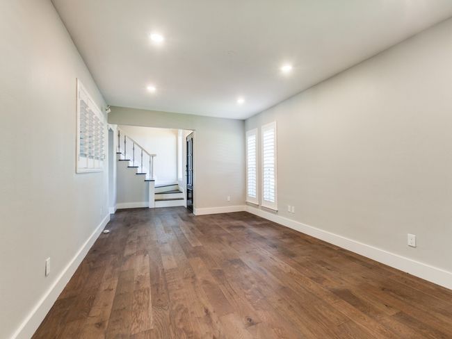 Empty room with stairway, dark wood-type flooring, recessed lighting, and baseboards | Image 10
