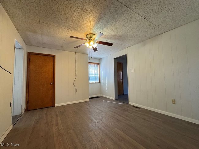 Unfurnished room featuring dark wood-style floors, ceiling fan, visible vents, and baseboards | Image 13
