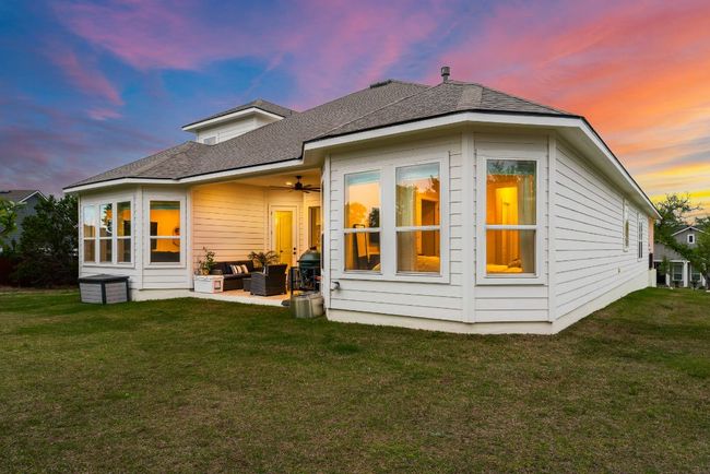 Back of house at dusk featuring outdoor lounge area, a lawn, a shingled roof, and a ceiling fan | Image 35