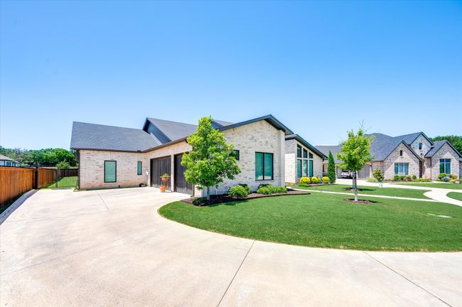 View of front of property featuring a front yard, fence, driveway, a garage, and brick siding | Image 4