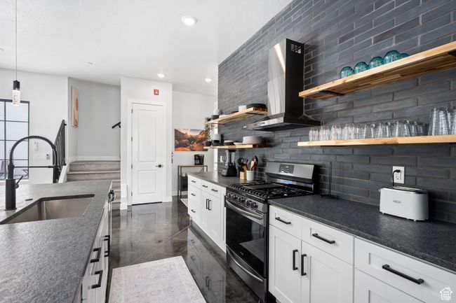 Kitchen featuring tasteful backsplash, sink, white cabinetry, wall chimney exhaust hood, and gas range | Image 11