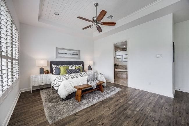 Bedroom featuring a tray ceiling, wood finished floors, connected bathroom, ceiling fan, and wood ceiling | Image 18