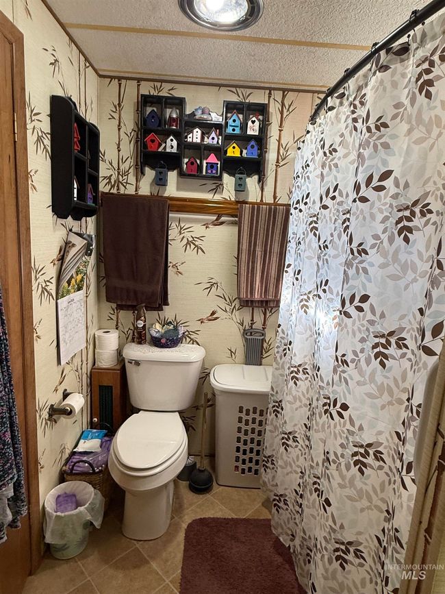 Bathroom with tile patterned flooring, a textured ceiling, and a shower with shower curtain | Image 15