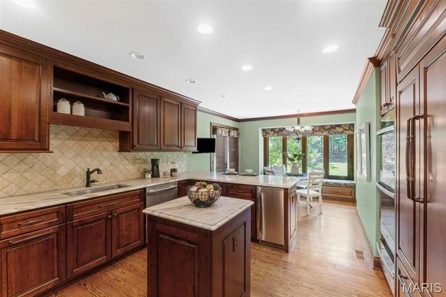 Kitchen with a peninsula, crown molding, a chandelier, light wood finished floors, and tasteful backsplash | Image 19