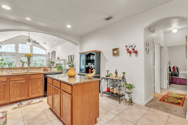 Kitchen featuring black dishwasher, arched walkways, ceiling fan, lofted ceiling, and light tile patterned flooring | Image 19