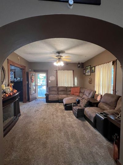 Carpeted living room featuring a textured ceiling and ceiling fan | Image 3