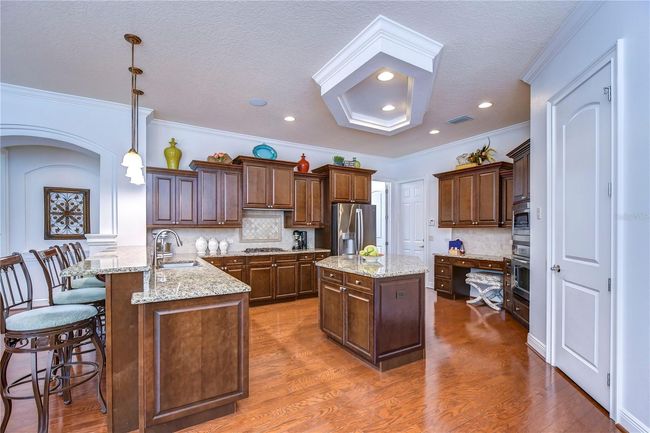 Boasting rich wood cabinetry, sleek granite countertops, and charming pendant lighting, it’s perfect for both weekday dinners and entertaining guests. | Image 11