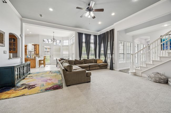 Living room with arched walkways, ornamental molding, a ceiling fan, light carpet, and recessed lighting | Image 30
