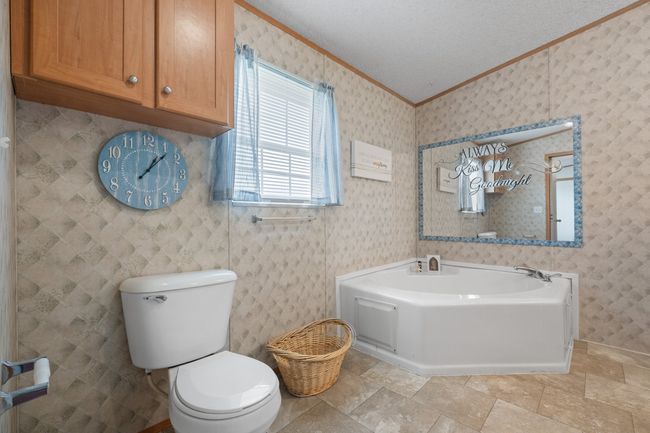 Full bathroom featuring crown molding, toilet, and a garden tub | Image 19