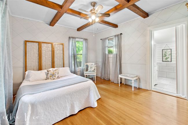 Main Bedroom featuring light oak looring, coffered beam ceiling, connected bathroom, and a exit to back porch. | Image 22