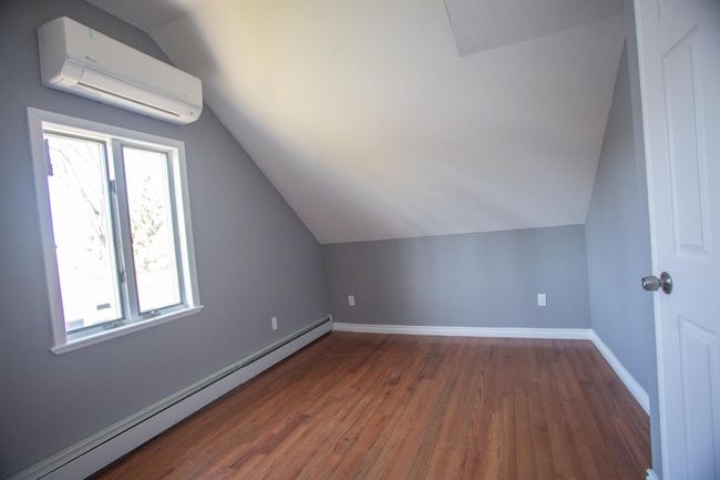 Bonus room featuring a wall mounted air conditioner, a baseboard radiator, dark hardwood / wood-style floors, and lofted ceiling | Image 23