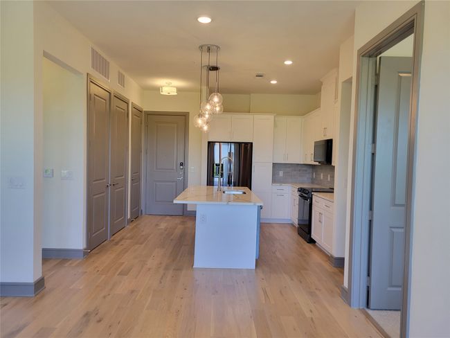Kitchen featuring black appliances, white cabinets, decorative backsplash, light wood finished floors, and recessed lighting | Image 6