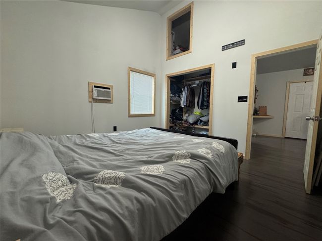 Bedroom with wood finished floors, a high ceiling, a closet, and an AC wall unit | Image 9