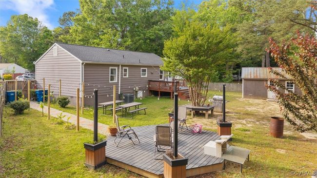 Back of property featuring a wooden deck, an outbuilding, a storage shed, a lawn, and fence | Image 31