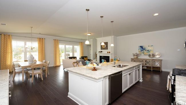 Kitchen with appliances with stainless steel finishes, a fireplace, dark wood finished floors, a sink, and a chandelier | Image 11