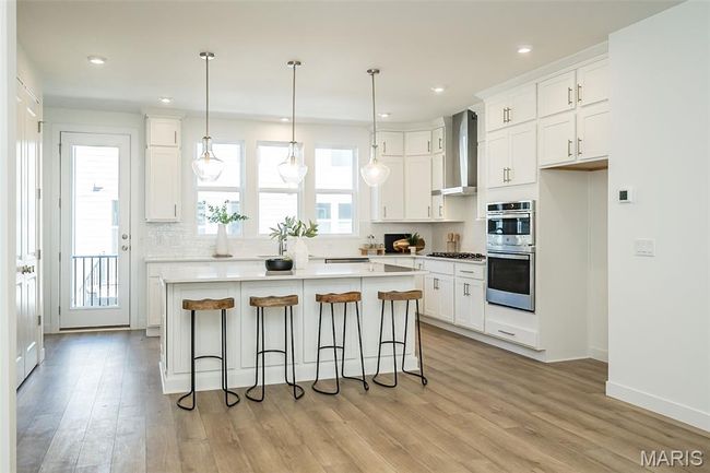 Kitchen featuring backsplash, white cabinets, light wood-type flooring, and recessed lighting | Image 4