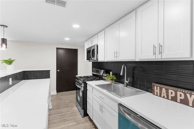 Kitchen featuring stainless steel appliances, white cabinets, light wood-style floors, light countertops, and recessed lighting | Image 32