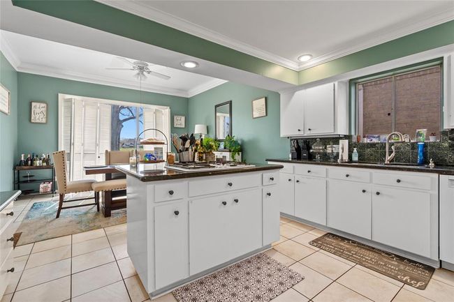 This spacious kitchen offers plenty of storage, counter space, and natural light. The central island provides additional workspace, perfect for meal prep or casual dining. Overlooking the dining area, this kitchen is ideal for cooking and entertaining with ease. | Image 18