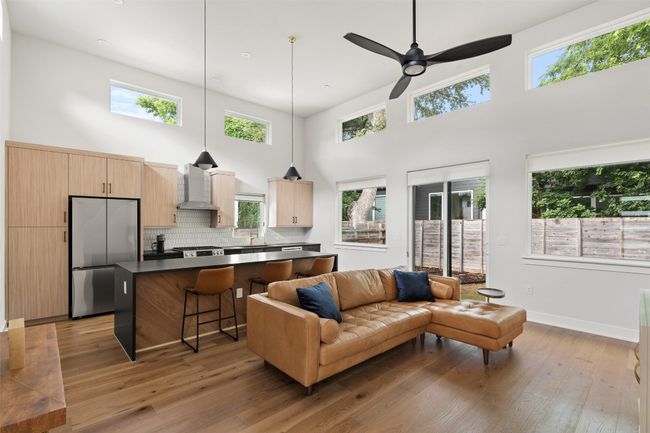 Living room with a towering ceiling, light wood-type flooring, and healthy amount of natural light | Image 5