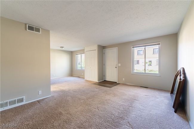 Carpeted empty room featuring baseboards, a textured ceiling, and visible vents | Image 5