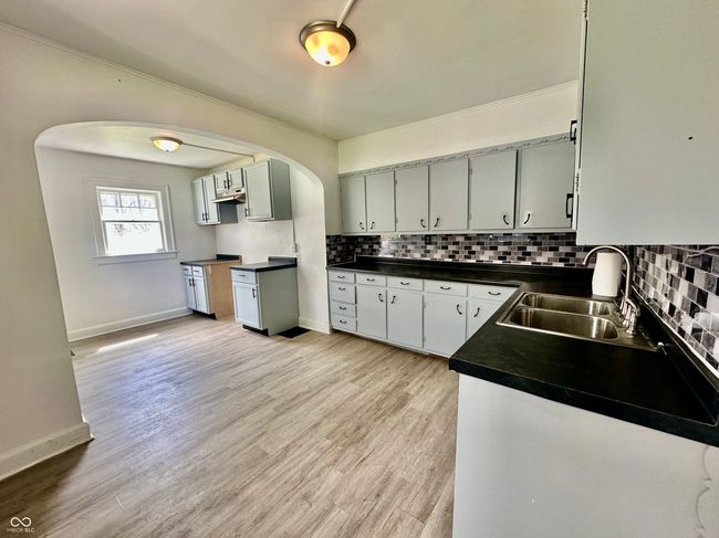 kitchen with a sink, decorative backsplash, dark countertops, and arched walkways | Image 30