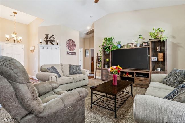 Carpeted living area featuring a chandelier, vaulted ceiling, and a ceiling fan | Image 13