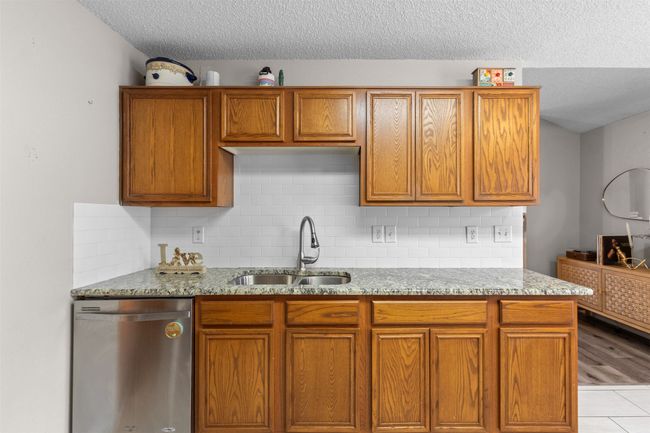 Kitchen featuring dishwasher, a sink, a textured ceiling, light stone counters, and tasteful backsplash | Image 15