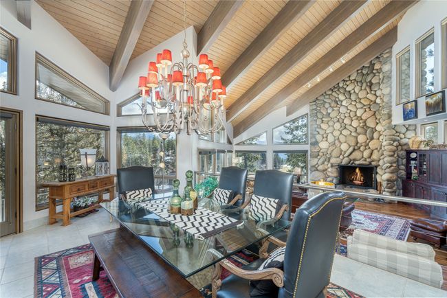 Tiled dining space with high vaulted ceiling, a notable chandelier, beamed ceiling, and a stone fireplace | Image 24
