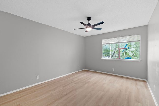Empty room featuring light wood-style flooring, a textured ceiling, a ceiling fan, and baseboards | Image 14
