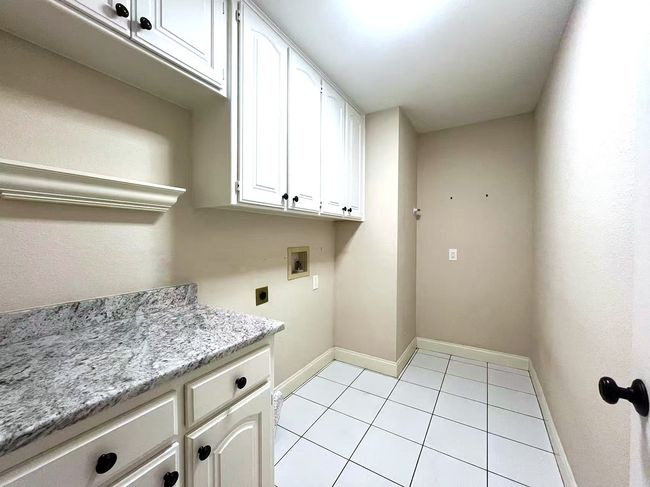 Washroom with cabinet space, hookup for a washing machine, hookup for an electric dryer, and light tile patterned floors | Image 30