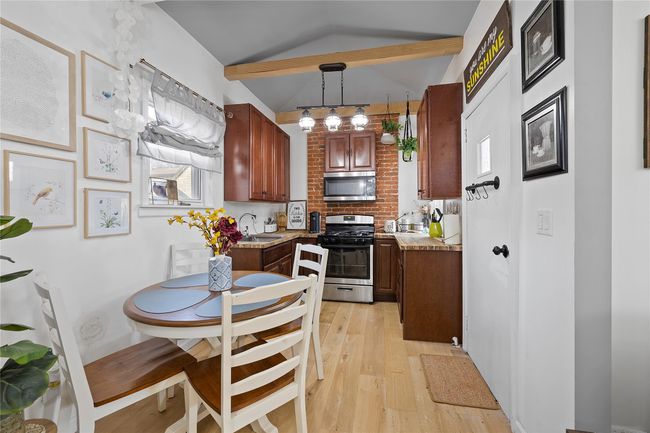 Kitchen featuring decorative light fixtures, sink, light wood-type flooring, lofted ceiling with beams, and stainless steel appliances | Image 6