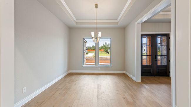 Unfurnished dining area with light wood-style floors, a chandelier, french doors, and a tray ceiling | Image 32