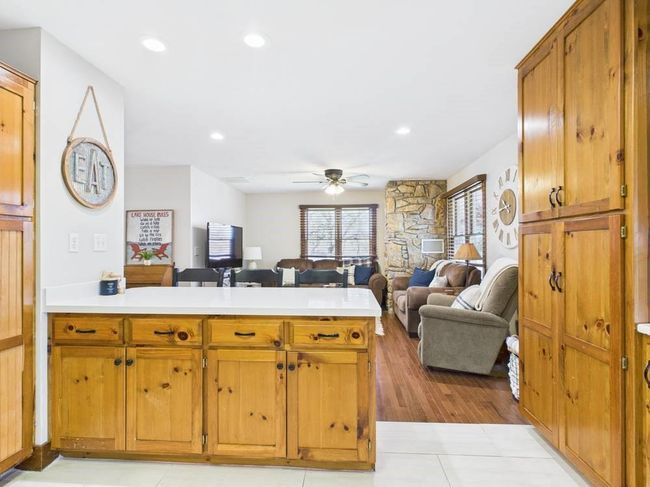 Kitchen featuring a peninsula, light countertops, open floor plan, and ceiling fan | Image 41