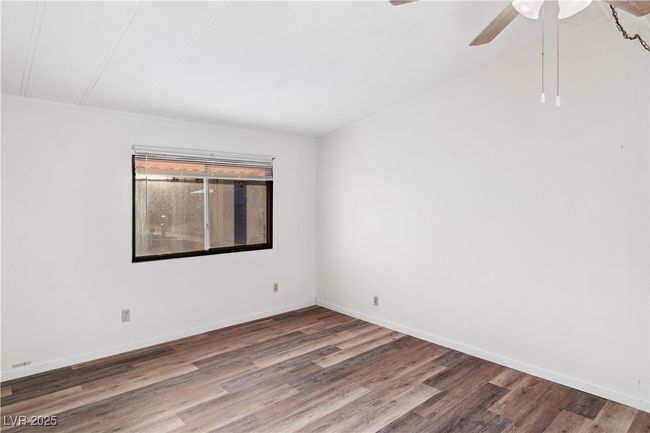 Primary bedroom with wood style floors, a ceiling fan, and baseboards | Image 19