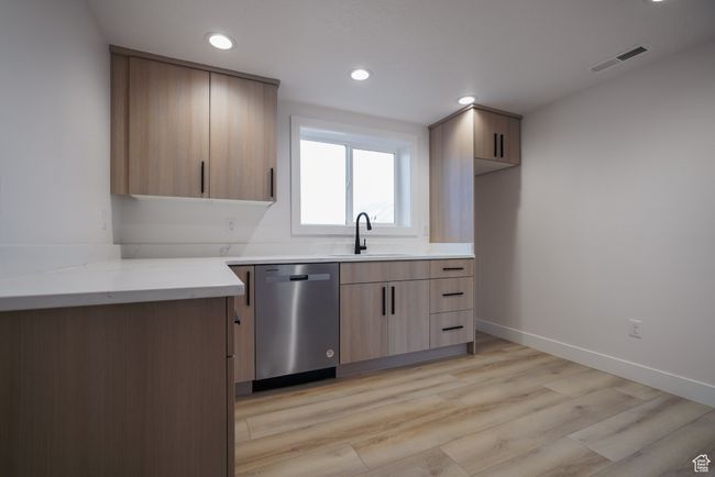 Kitchen featuring dishwasher, a sink, recessed lighting, light wood-type flooring, and baseboards | Image 24