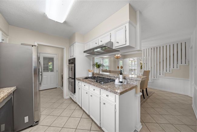 Double ovens, large cooktop, SS appliances and breakfast bar connecting to the dining space. | Image 7