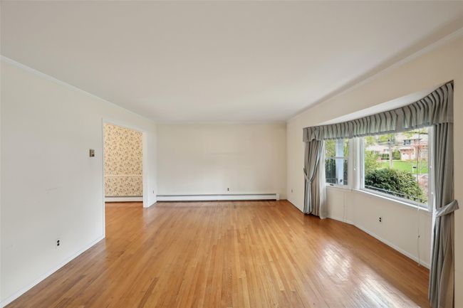 Spare room with light wood-type flooring, baseboards, ornamental molding, and a baseboard radiator | Image 12
