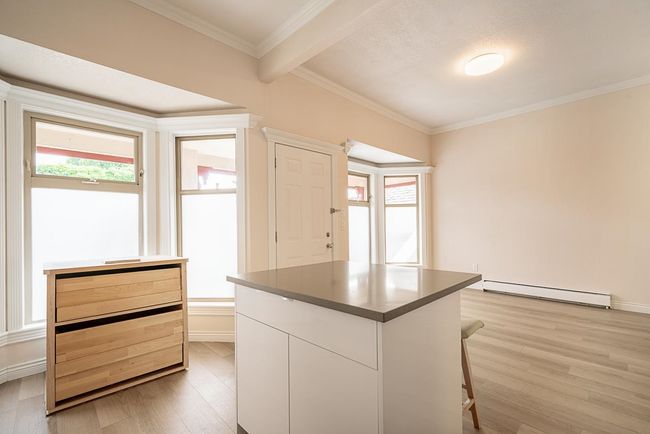 Kitchen with a baseboard heating unit, light wood-type flooring, a breakfast bar, a center island, and ornamental molding | Image 12