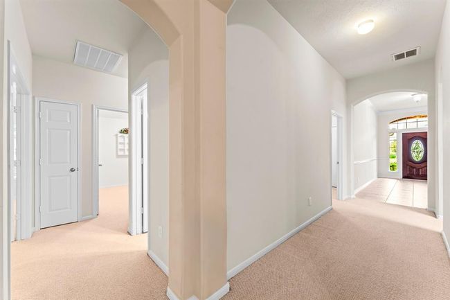 This hallway leads to the secondary bedrooms, offering a private wing separate from the main living spaces. Arched doorways and soft lighting add architectural interest along the way. | Image 18
