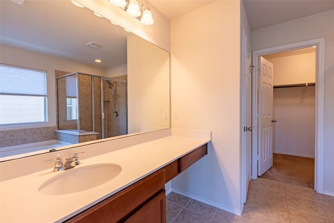 Bathroom with a stall shower, vanity, a walk in closet, tile patterned floors, and a bath | Image 14