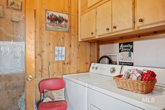 Laundry room featuring cabinet space, washing machine and clothes dryer, and wood walls | Image 25