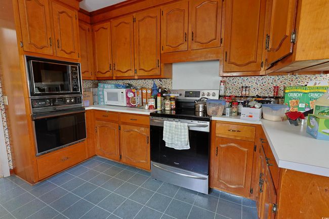 Kitchen featuring black appliances, light countertops, dark tile patterned flooring, and backsplash | Image 7