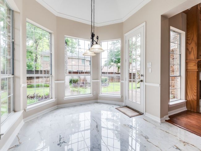 Dining area with healthy amount of natural light, marble like tiled floors, and crown molding. Access the back yard from this area. | Image 15