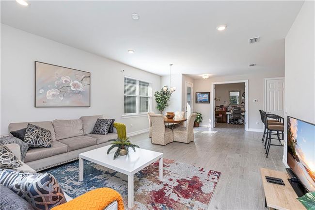 Living room featuring light wood-style floors, baseboards, visible vents, and an inviting chandelier | Image 7