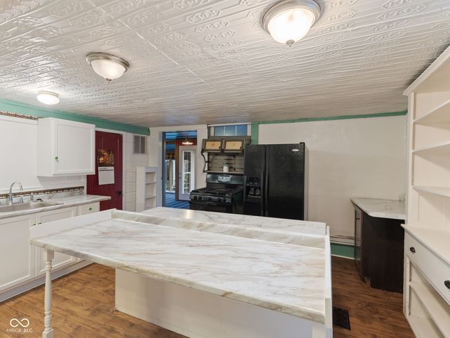 kitchen featuring a sink, white cabinets, black appliances, and wood finished floors | Image 12