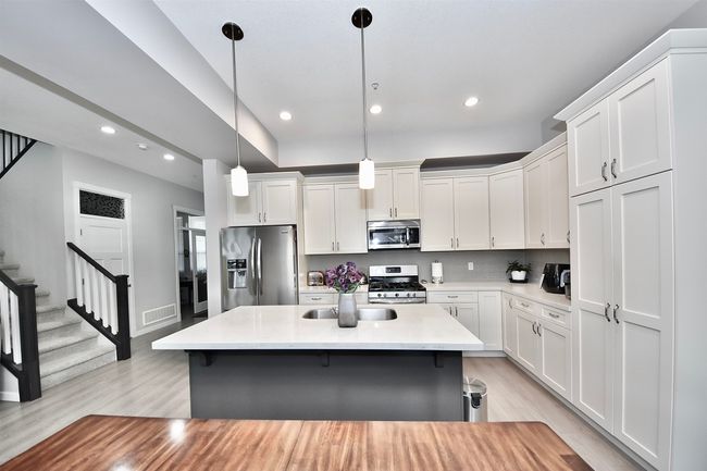 Kitchen with stainless steel appliances, light wood-type flooring, white cabinetry, recessed lighting, and light countertops | Image 4