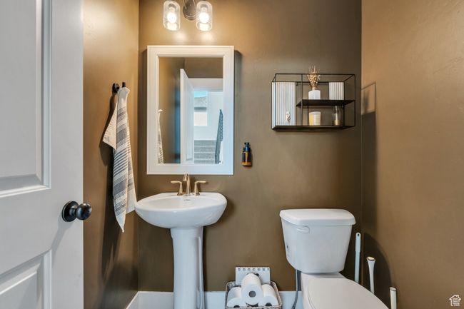 Half bathroom featuring an inviting chandelier and toilet | Image 12